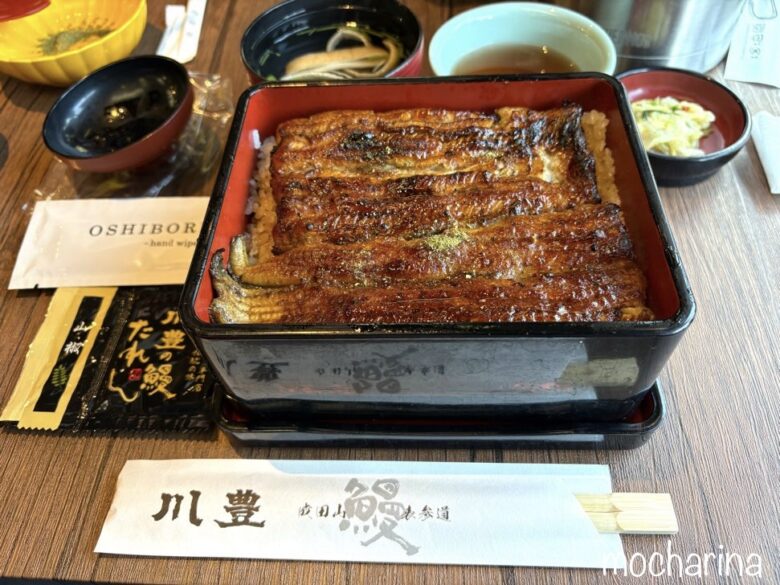 蓋を開けた上うな重の写真。付属の箸やおしぼりなどを添えている様子。