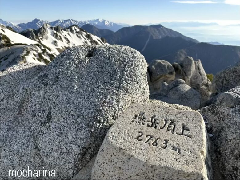 燕岳山頂の写真。山並みと岩に書かれた「燕岳山頂」と標高が書いてある様子。
