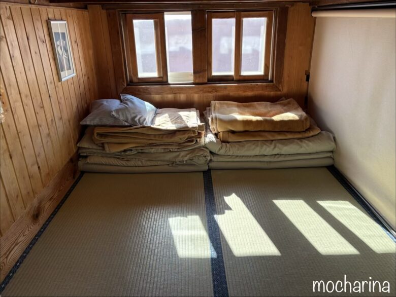 燕山荘のお部屋の写真。小さなスペースに畳んだ布団が2組置いてある様子。