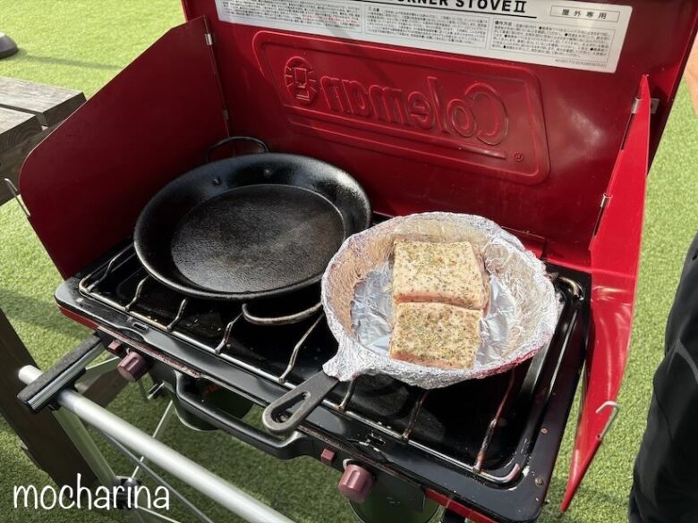 バーベキューコンロで塊肉を焼く写真。コンロ置いたスキレットで燻製肉を作る様子。