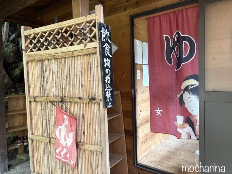 白骨温泉の入り口の写真。入り口と日本画女性の赤いのれんが掛かっている様子。