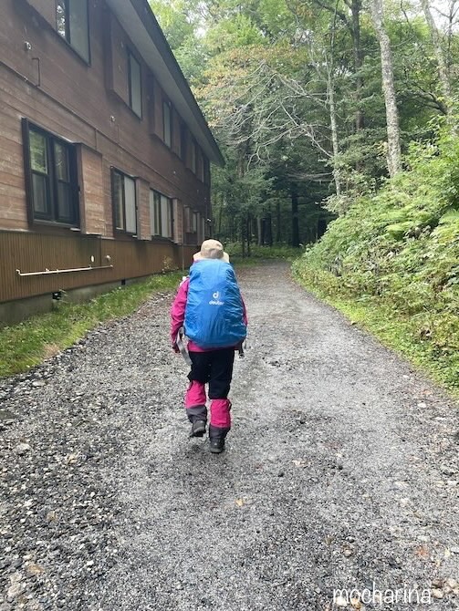 山荘横の登山道を歩いている写真。レインウェア・レッグウォーマー、ザックカバーをして歩いている様子。
