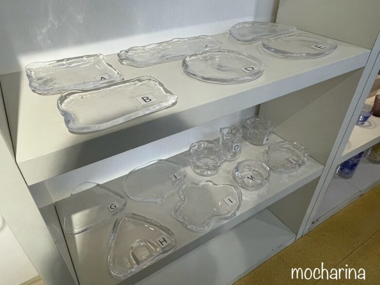見本のガラスの作品15点の写真。ガラス制作体験用のお皿や鉢が並んでいる様子。